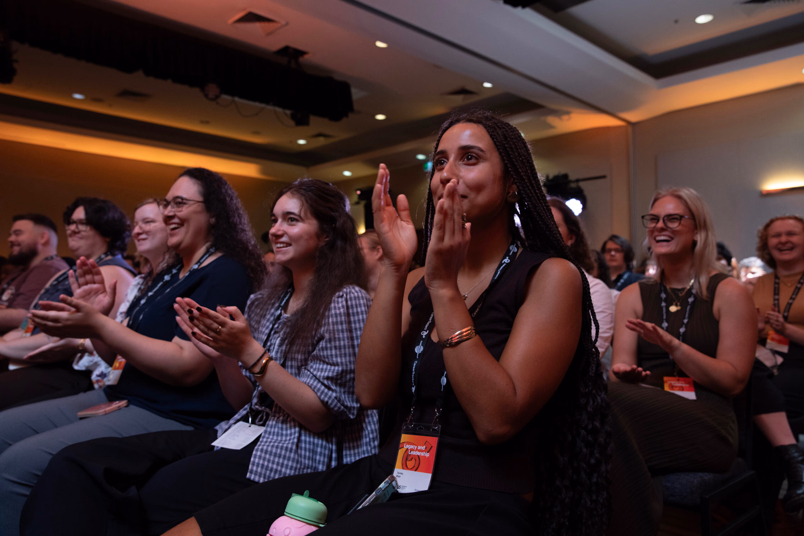 Students applauding from the audience at a CareerTrackers leadership conference.
